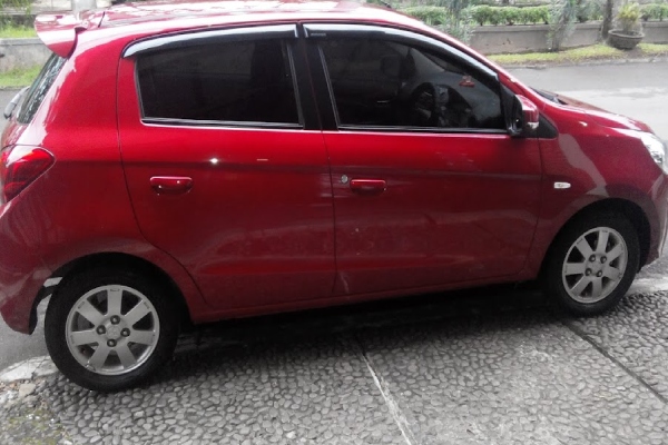 Mitsubishi Mirage merah di jalan kota